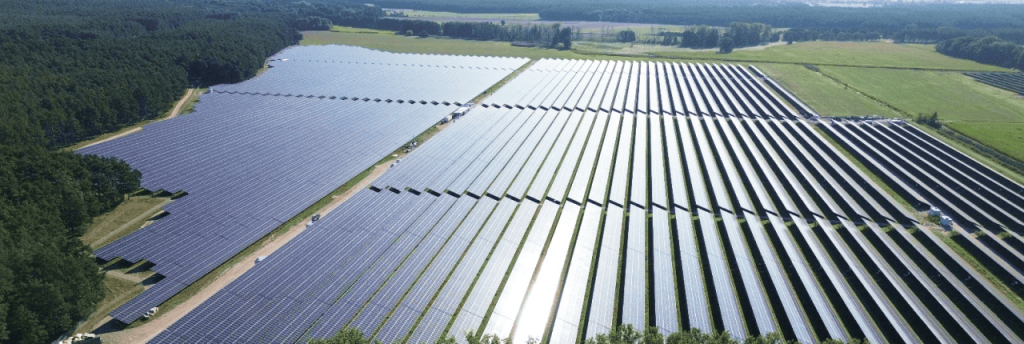 Gro&szlig;fl&auml;chiger Solarpark Frankenf&ouml;rde mit dicht angeordneten Solarmodulen neben einem Waldgebiet.